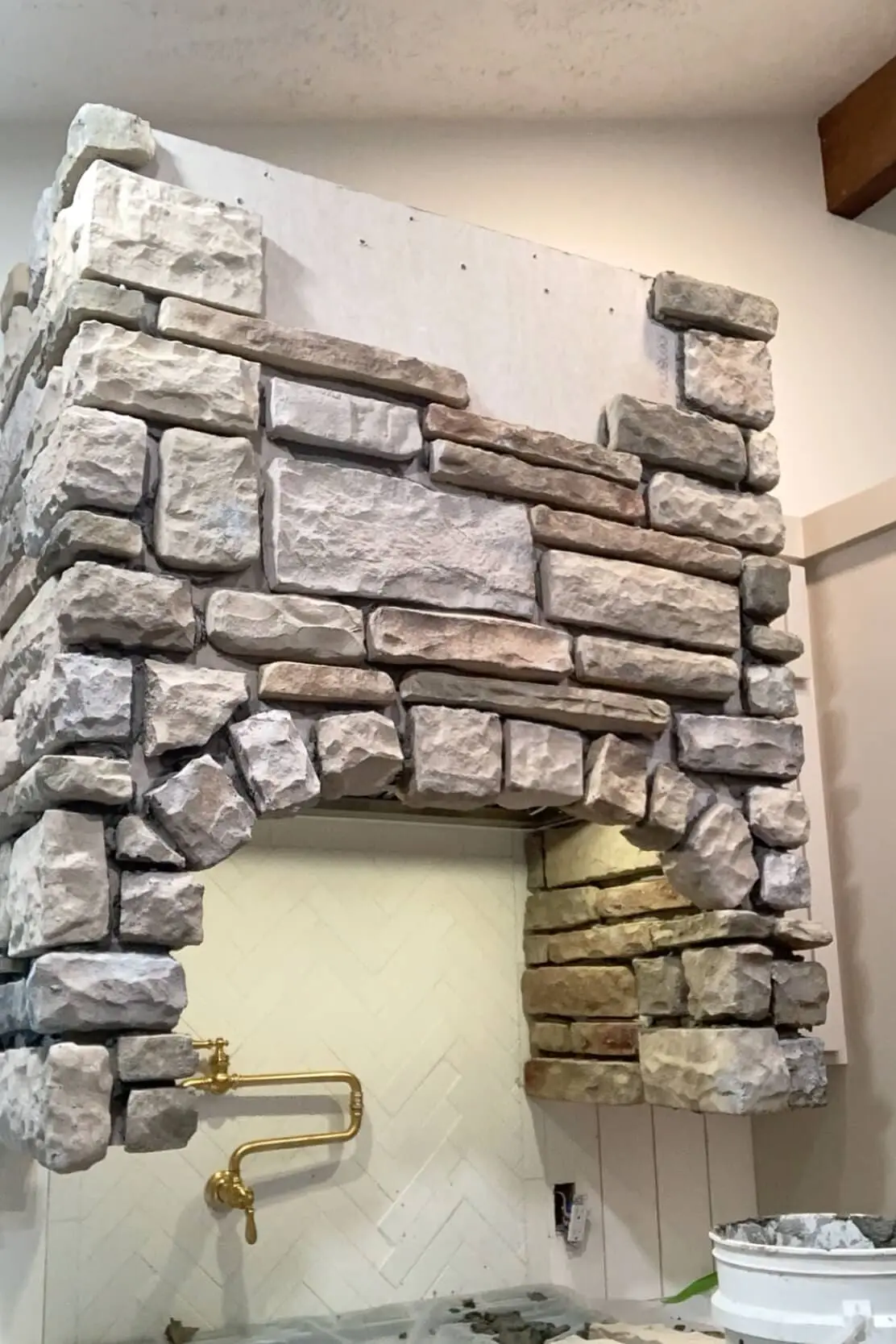 Adding stone to a stone range hood surround.